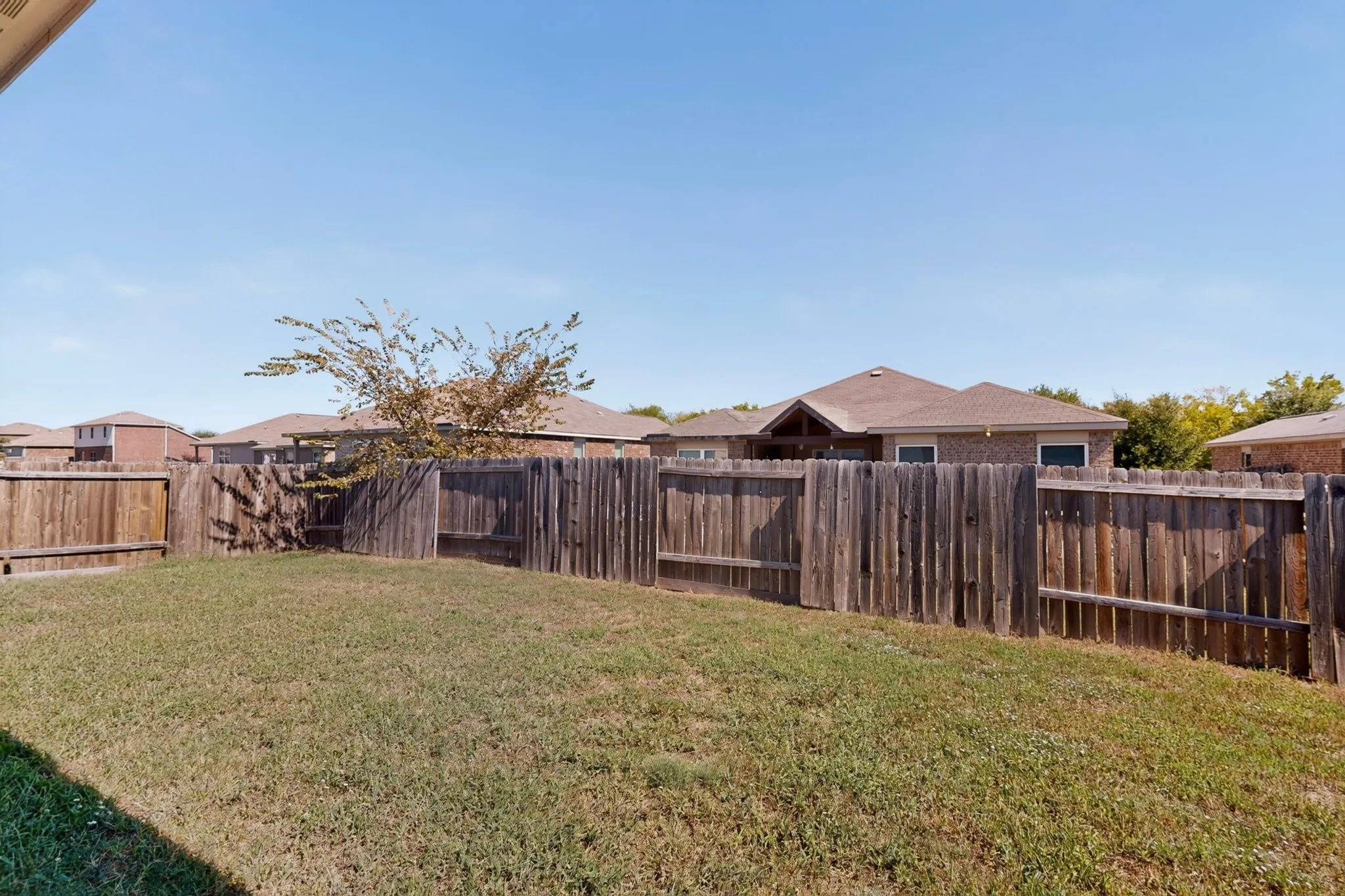 Enclosed backyard featuring wood privacy fencing and a grass lawn