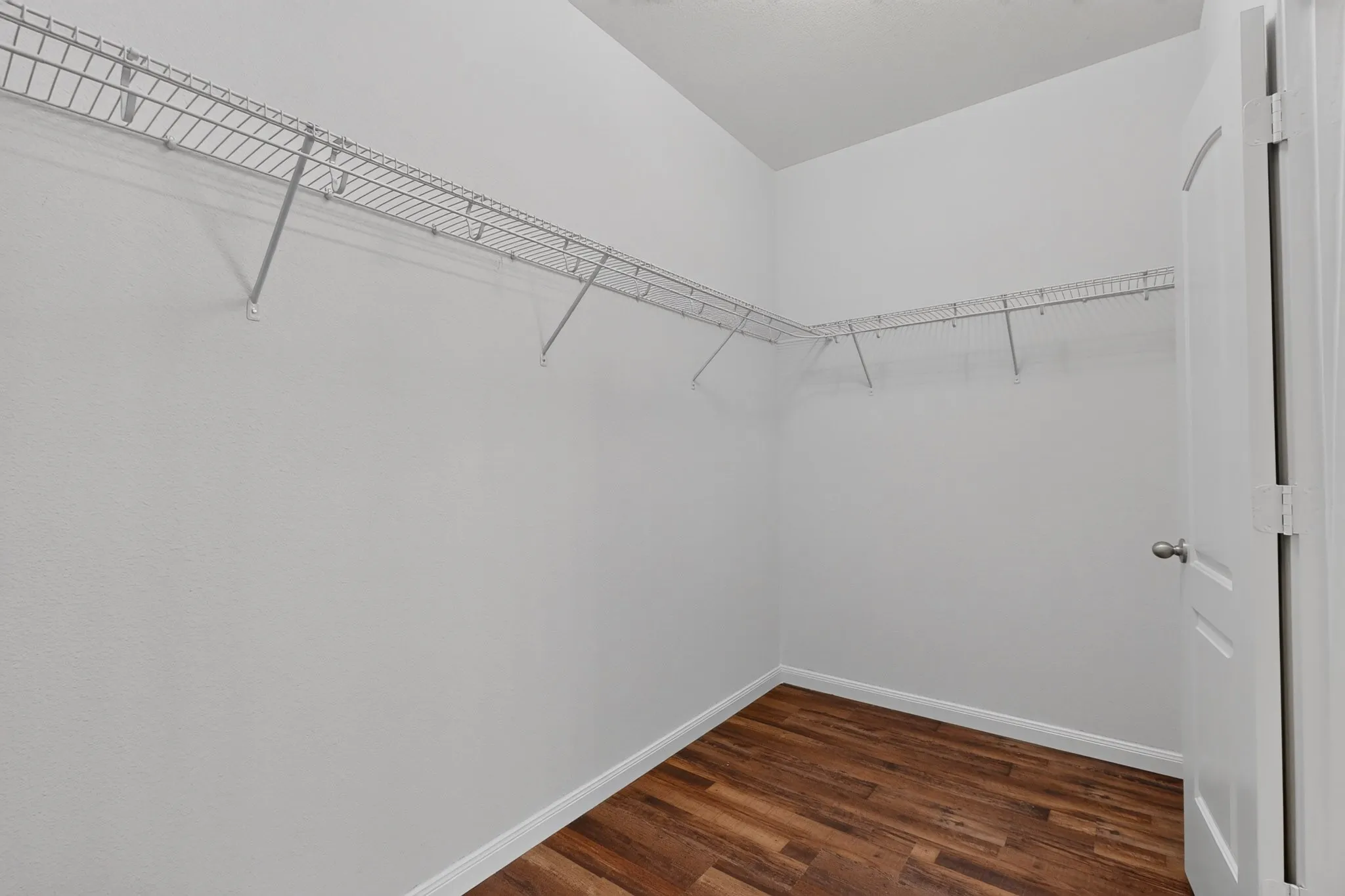 Spacious closet featuring wire shelving, wood-finish flooring, and a white paneled door