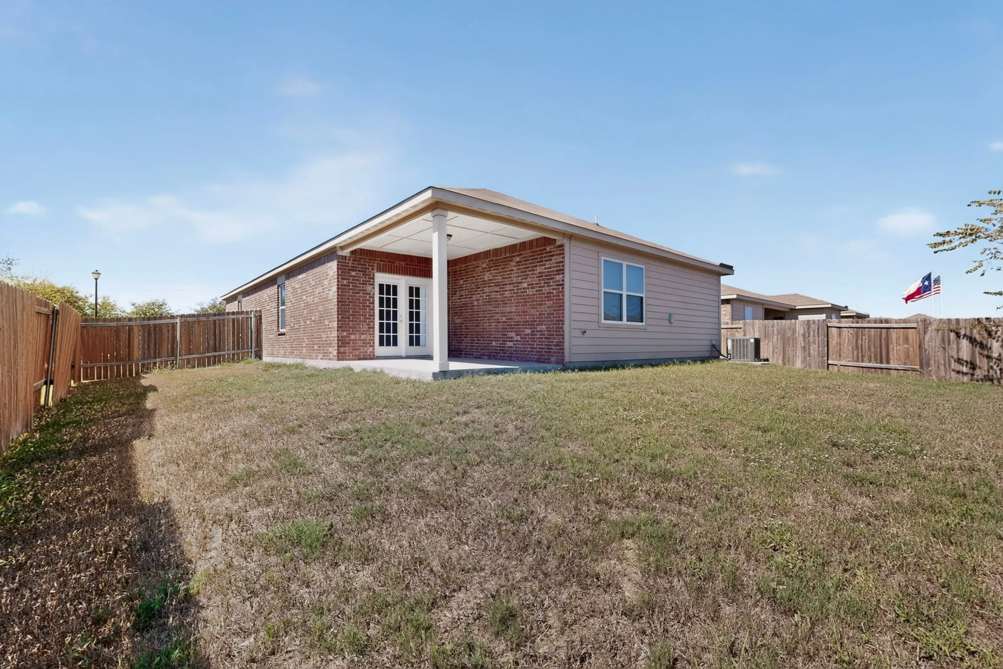 Brick and siding exterior with a covered patio, double-pane windows, and a wood privacy fence