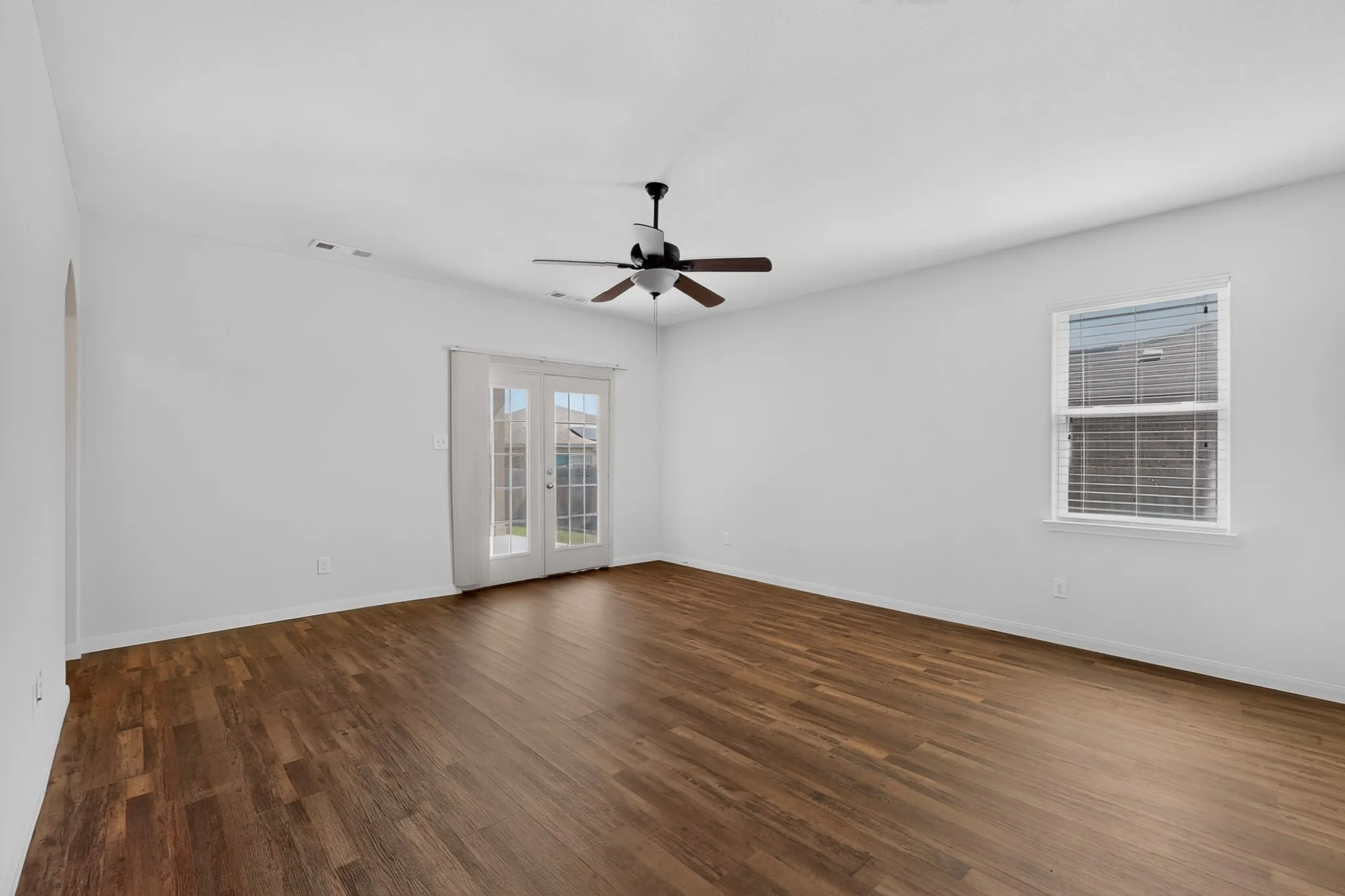 Wood-finish flooring, white walls, and a ceiling fan with light fixture