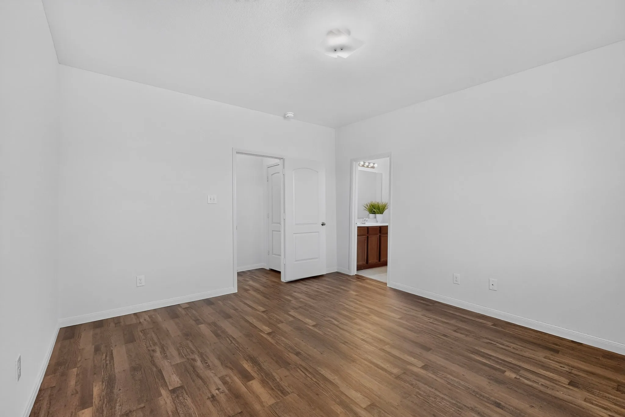 Wood-finish flooring, white walls, and a ceiling-mounted light fixture