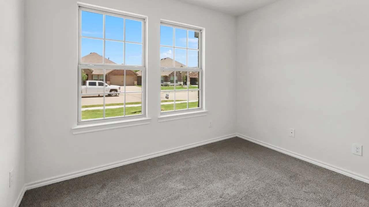 Bright interior space featuring two grid-pattern windows, neutral wall paint, white baseboards, and soft gray carpeting