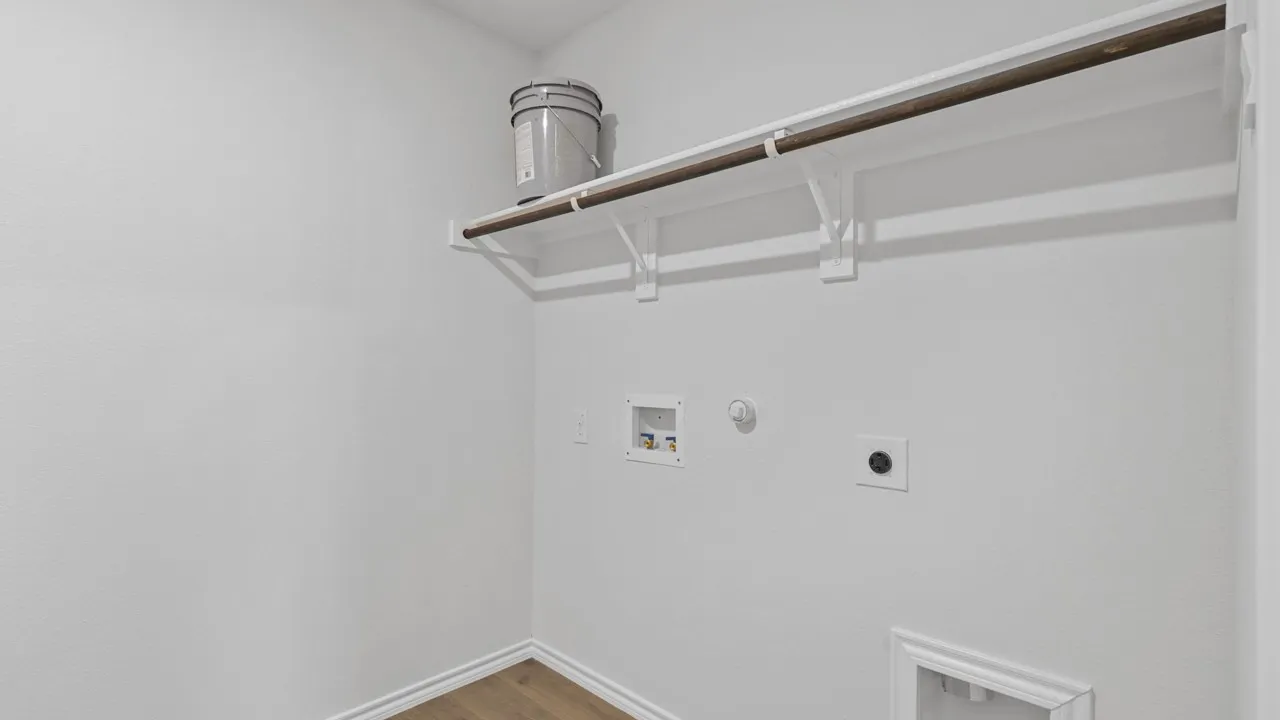 Laundry area featuring wood-finish flooring, white walls, and a built-in shelf with a hanging rod