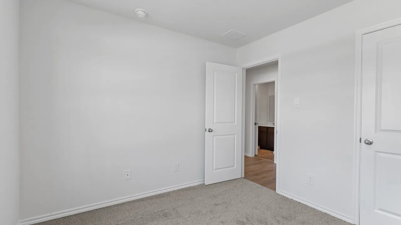 Carpeted room featuring light-toned walls, white trim, and a white interior door with a silver-toned knob