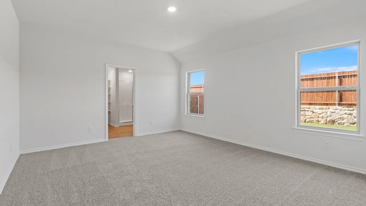 Spacious room featuring vaulted ceilings, light-toned carpeting, and two windows