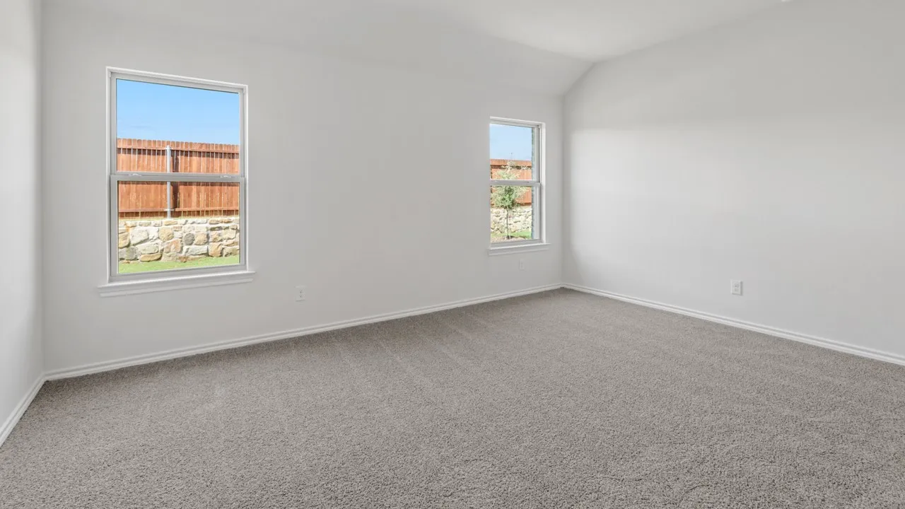 Bright room featuring neutral carpeting, white walls, two windows, and a vaulted ceiling