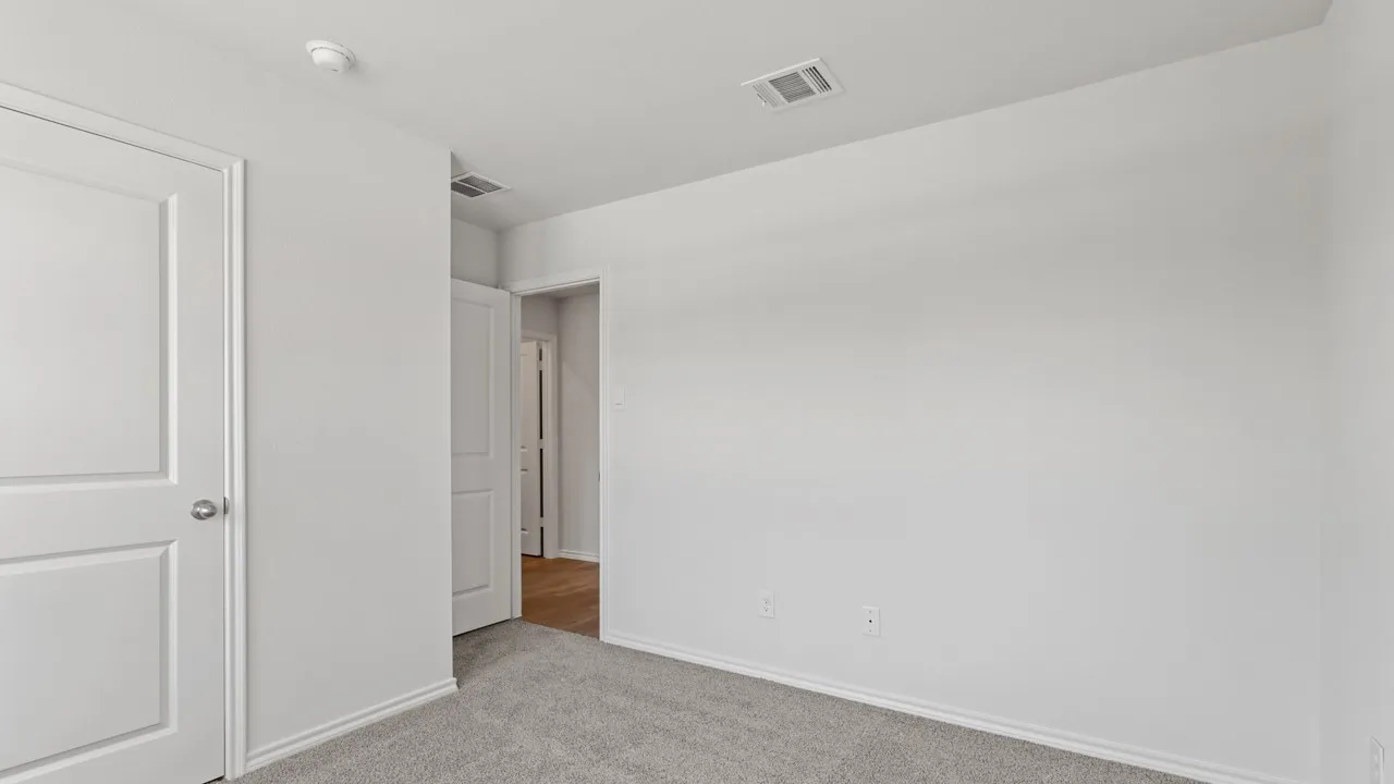Carpeted room featuring light gray walls, white baseboards, and a white two-panel interior door