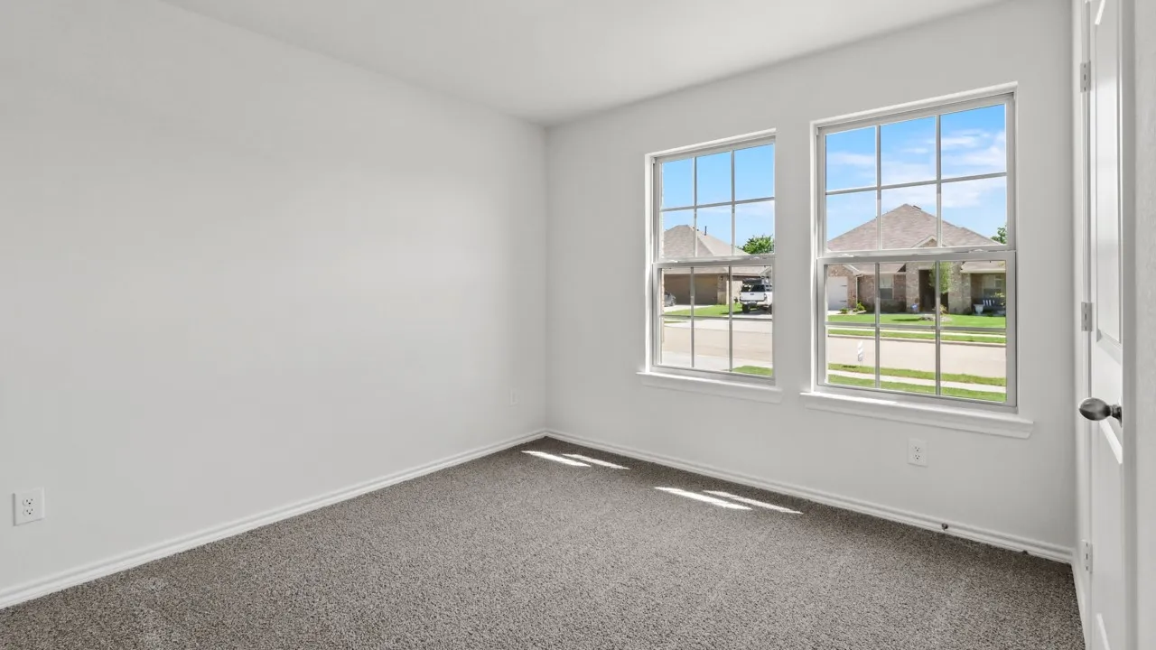 Room featuring two sash windows with grilles, white trim, and light gray carpet