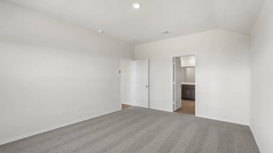 Spacious room featuring light gray carpeting, white walls, and a vaulted ceiling with a recessed light fixture