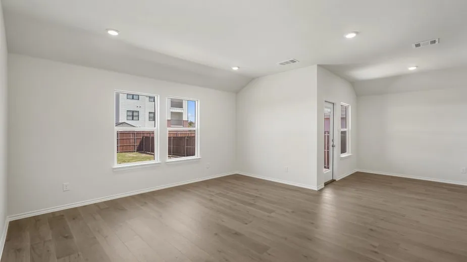Spacious room featuring wood-finish flooring, recessed lighting, and multiple windows