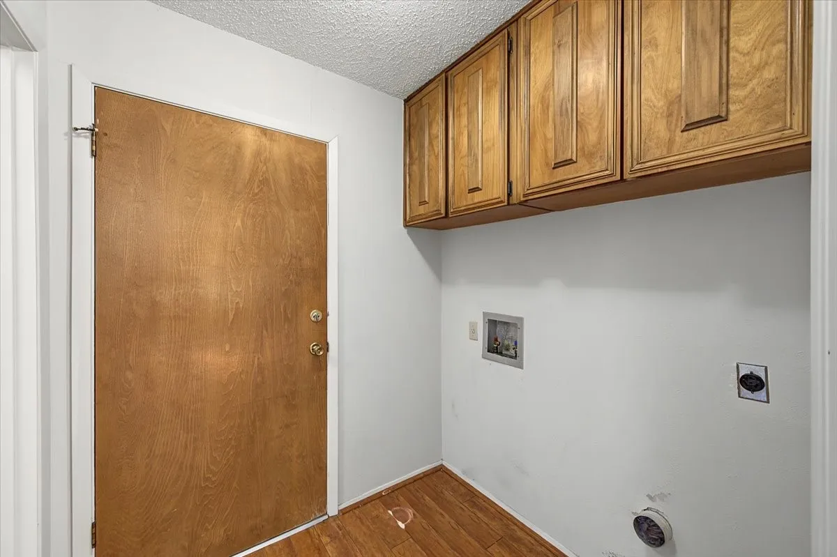 Wood-finish flooring with overhead cabinetry and a built-in utility sink