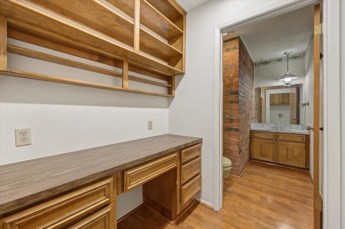 Built-in wood-finish desk with storage, integrated shelving, and wood-finish flooring