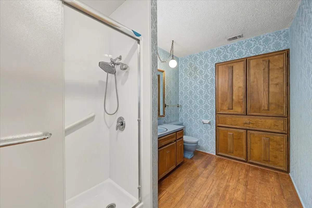 Shower with sliding glass enclosure, chrome fixtures, and a grab bar