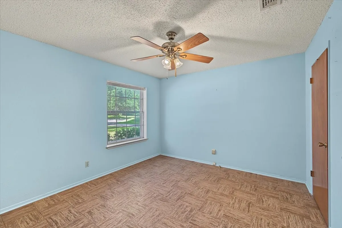 Room featuring wood-look flooring, a window with exterior views, and a ceiling fan with integrated lighting