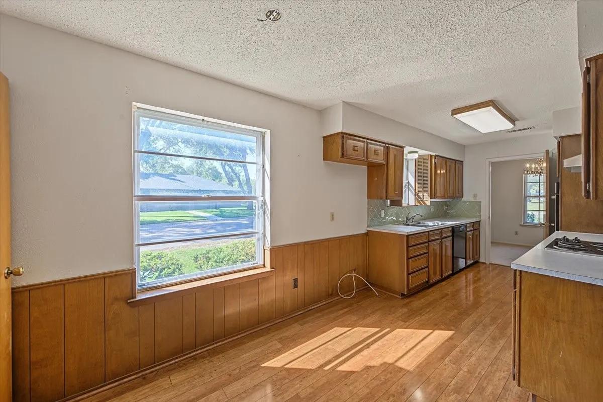 Kitchen featuring wood-finish flooring, wood cabinetry, white countertops, and a tile backsplash