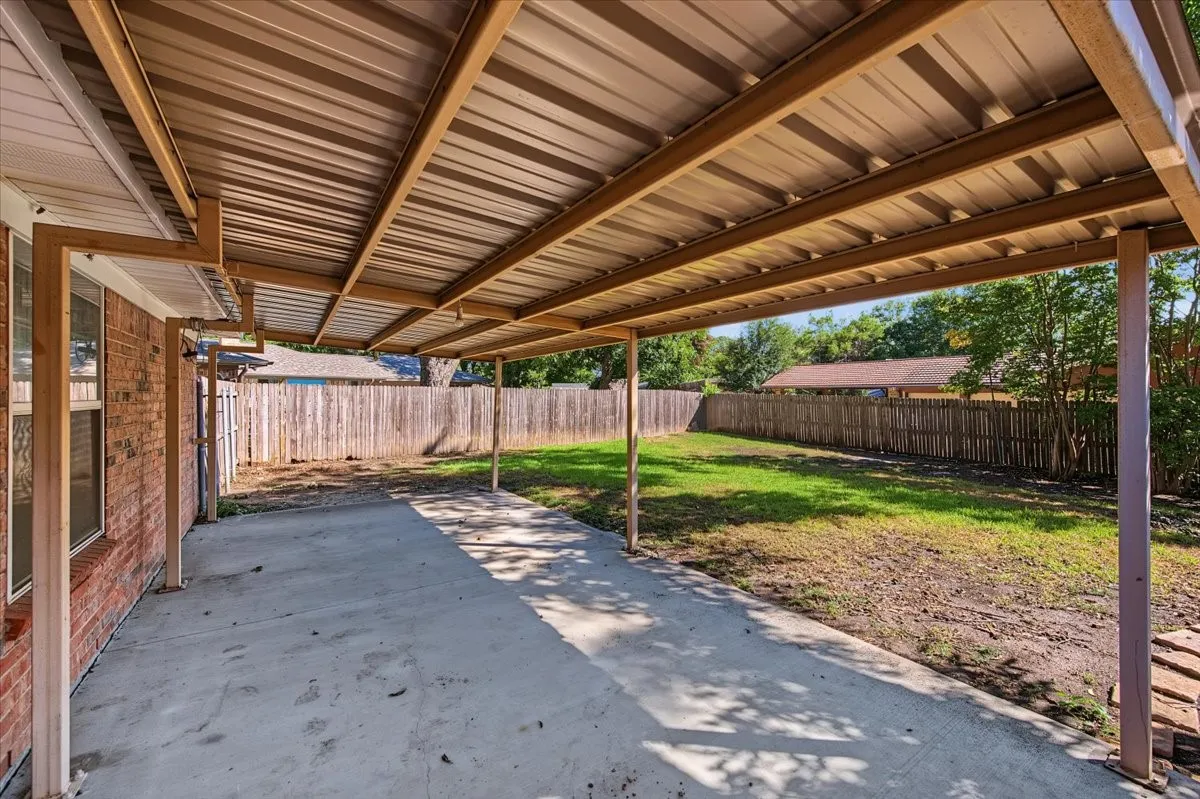 Covered patio area with concrete surfacing, corrugated metal roof, and metal support posts
