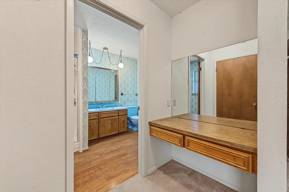 Built-in vanity with wood-finish countertop and mirrored wall