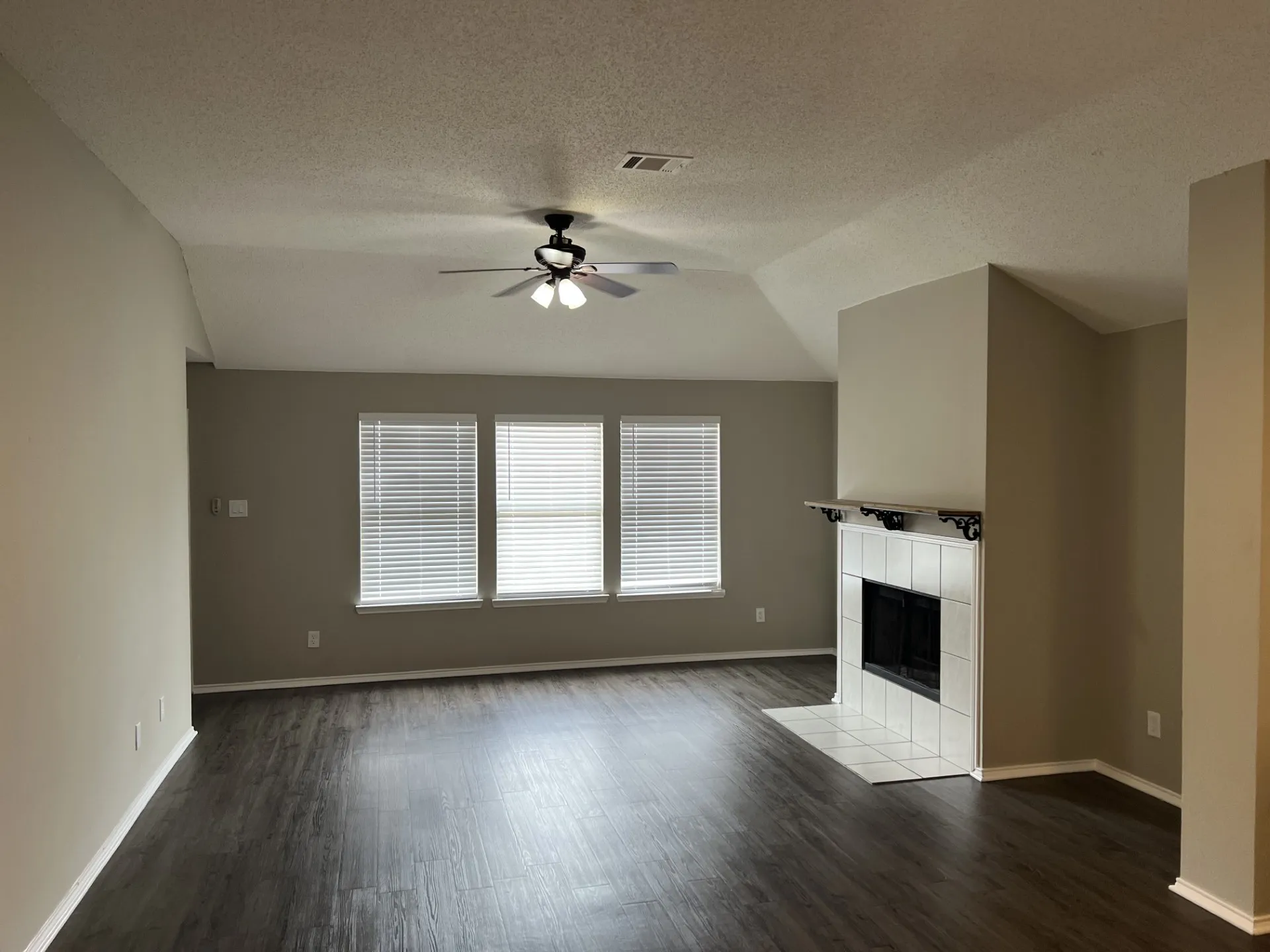 Wood-finish flooring, vaulted ceiling, built-in fireplace with tile surround and mantle, and ceiling fan