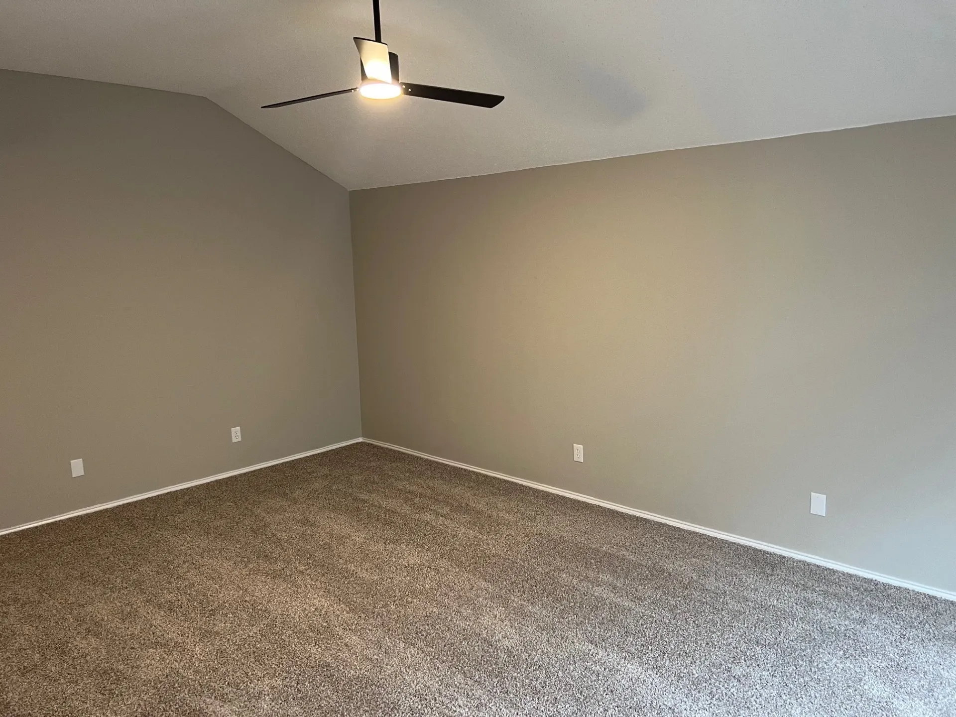Vaulted ceiling featuring a ceiling fan with integrated lighting, neutral wall paint, and textured carpeting