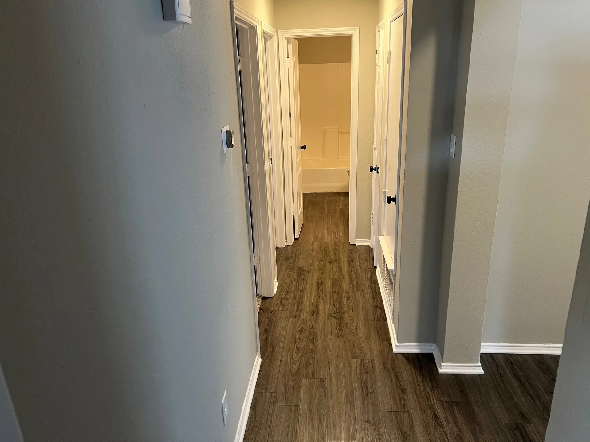 Hallway with wood-finish flooring, light-toned walls, and white trim