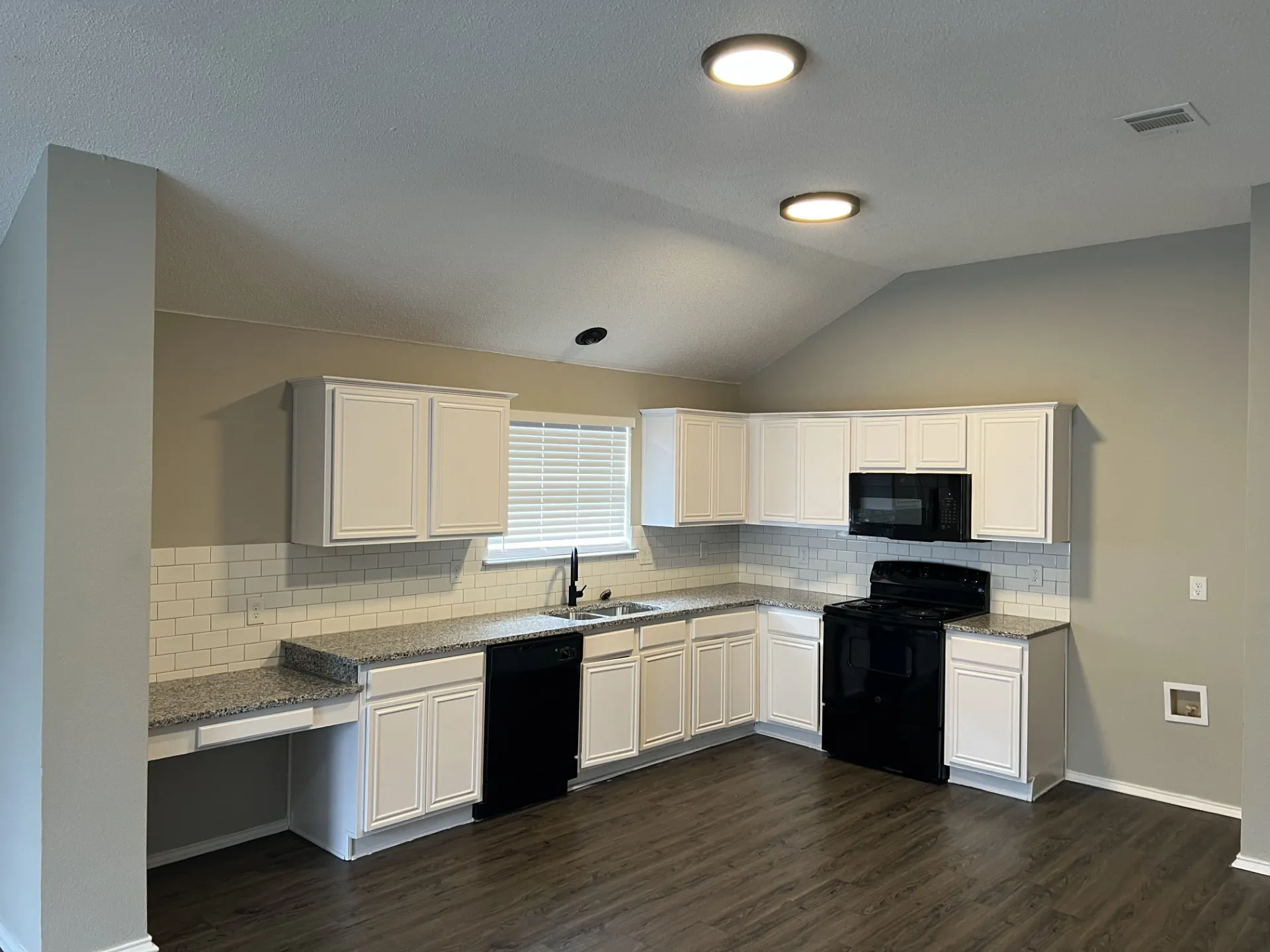 Kitchen featuring white cabinetry, speckled countertops, subway tile backsplash, and wood-finish flooring