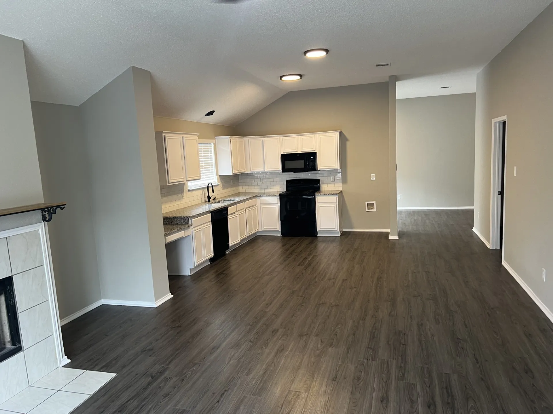 Kitchen featuring white cabinetry, black appliances, tile backsplash, and light-colored countertops