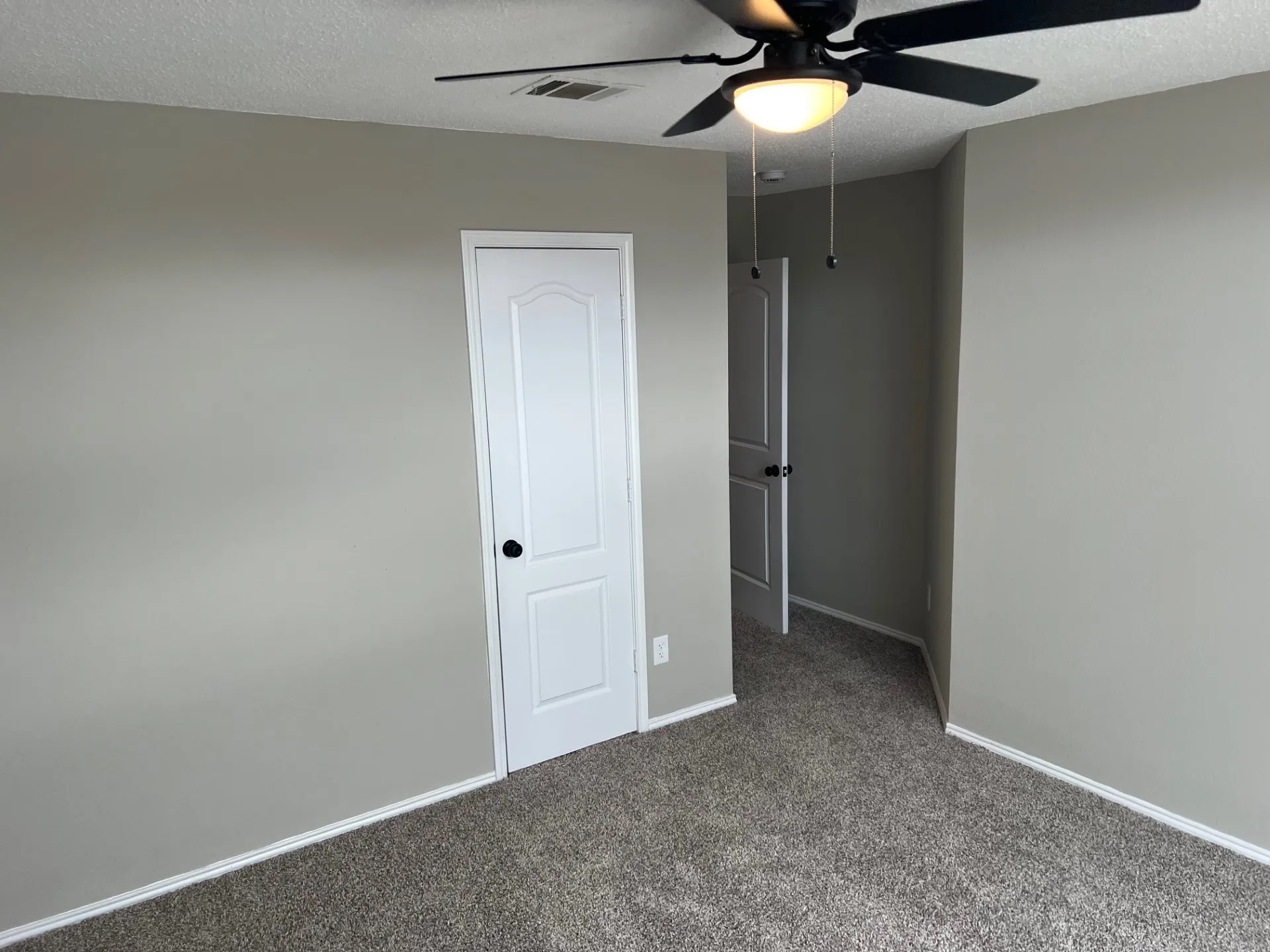 Neutral wall color, textured carpeting, panel doors, and a ceiling fan with integrated lighting