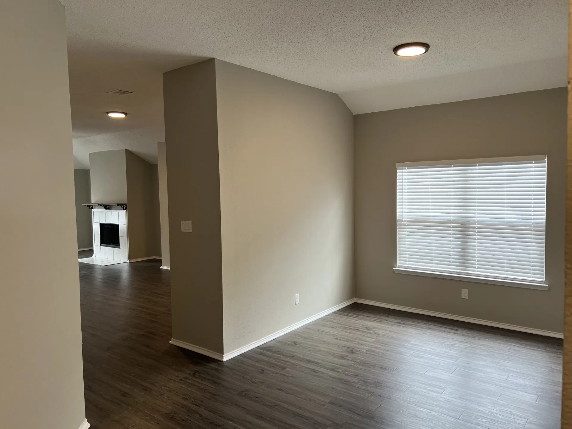 Wood-finish flooring throughout, recessed ceiling lighting, window with blinds, and white baseboards