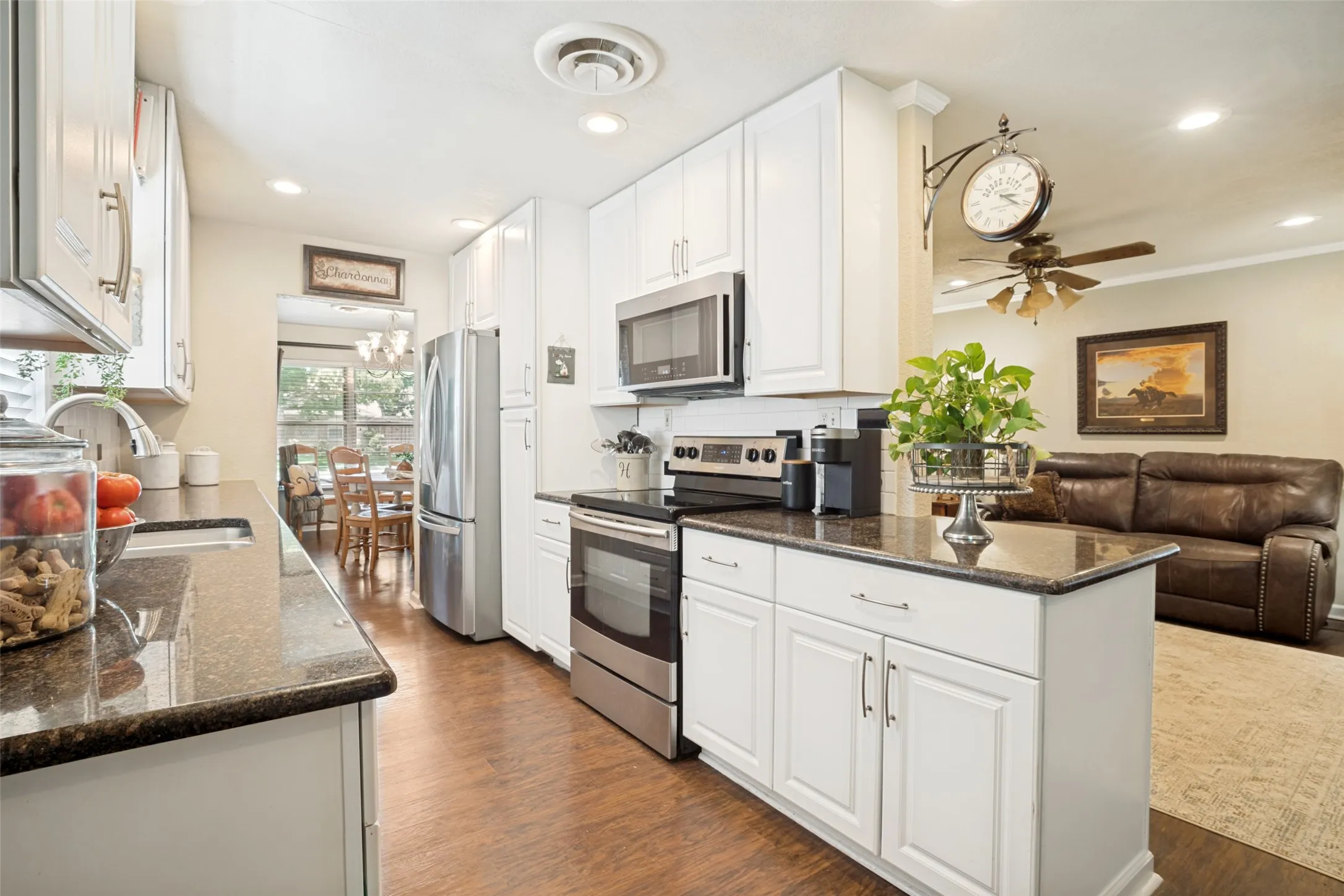 Full kitchen with white cabinetry, dark stone countertops, and stainless steel appliances