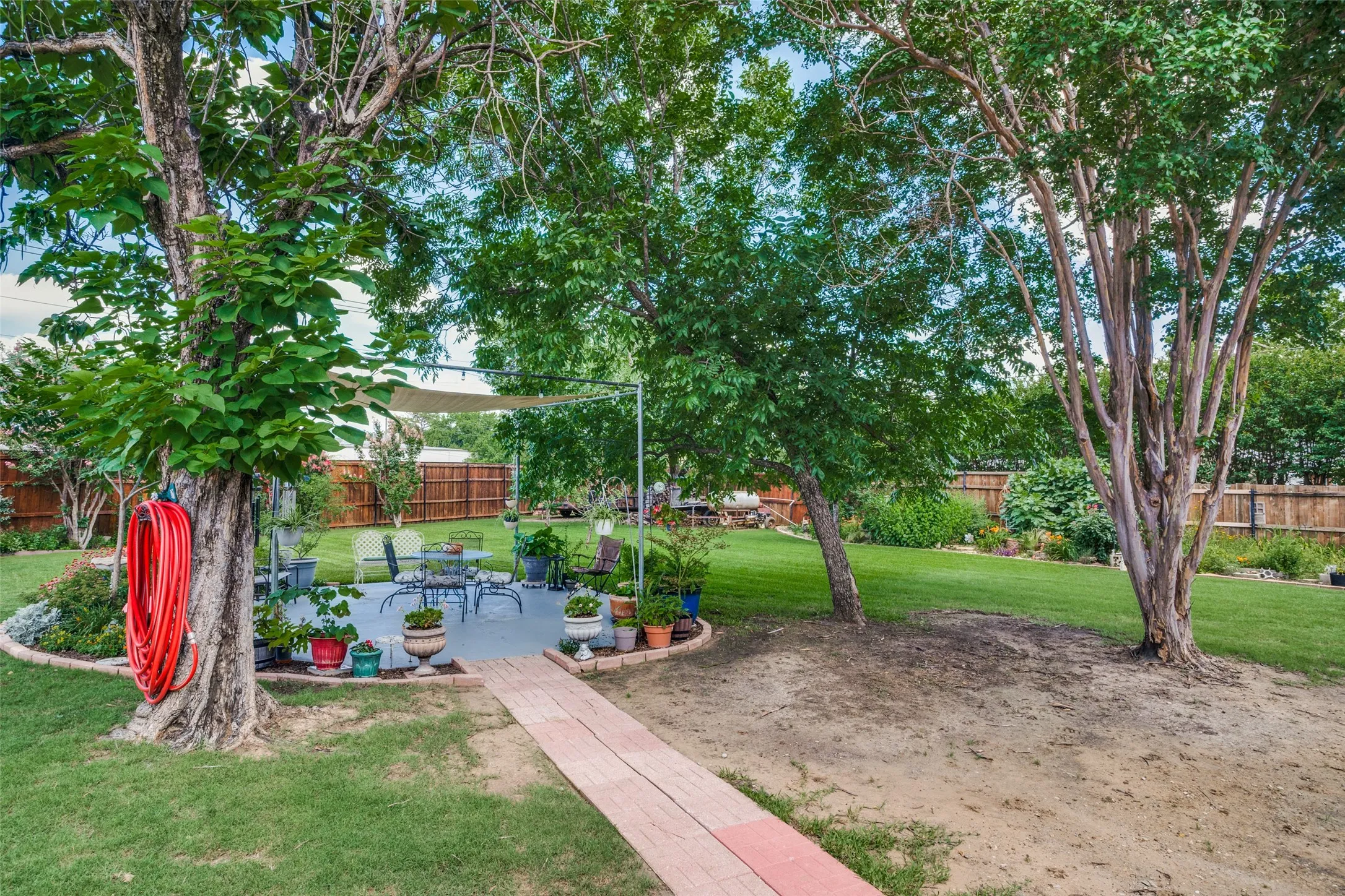 Expansive backyard with a manicured lawn, established trees, and a concrete patio