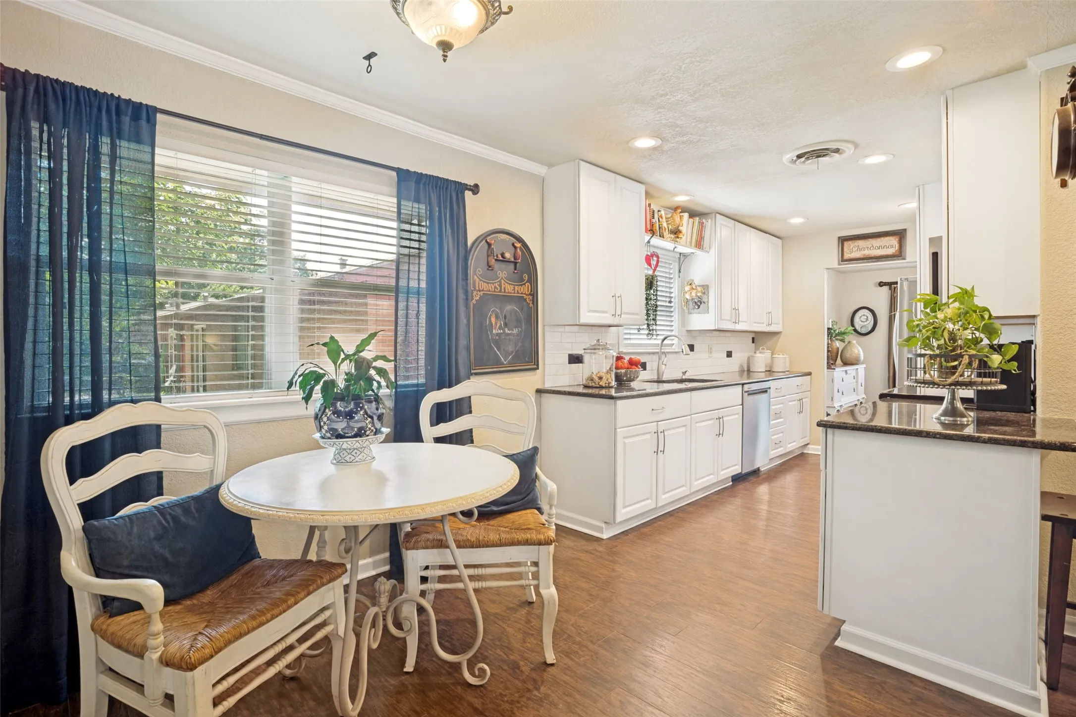 Kitchen featuring white cabinetry, dark countertops, a window with blinds, wood-like flooring, and recessed lighting