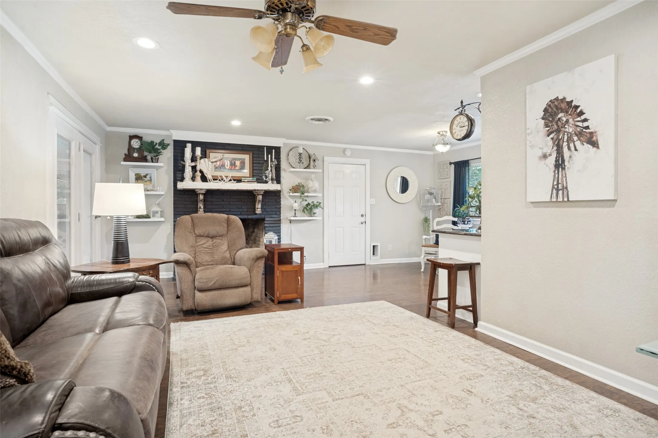 Recessed lighting, wood-like flooring, ceiling fan, built-in shelving, and a dark-painted fireplace