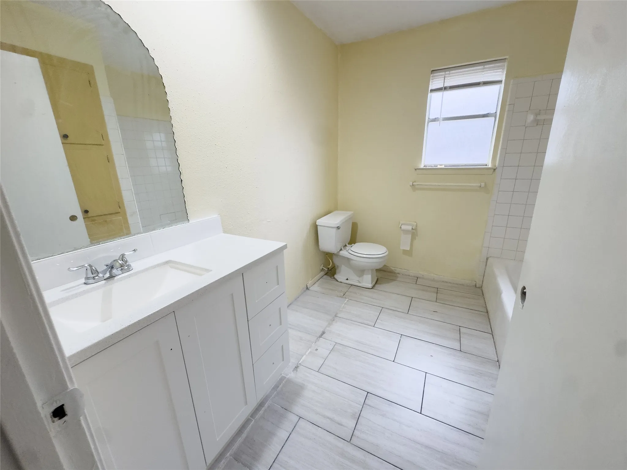 Modern vanity with integrated sink, chrome faucet, white countertop, and arched mirror