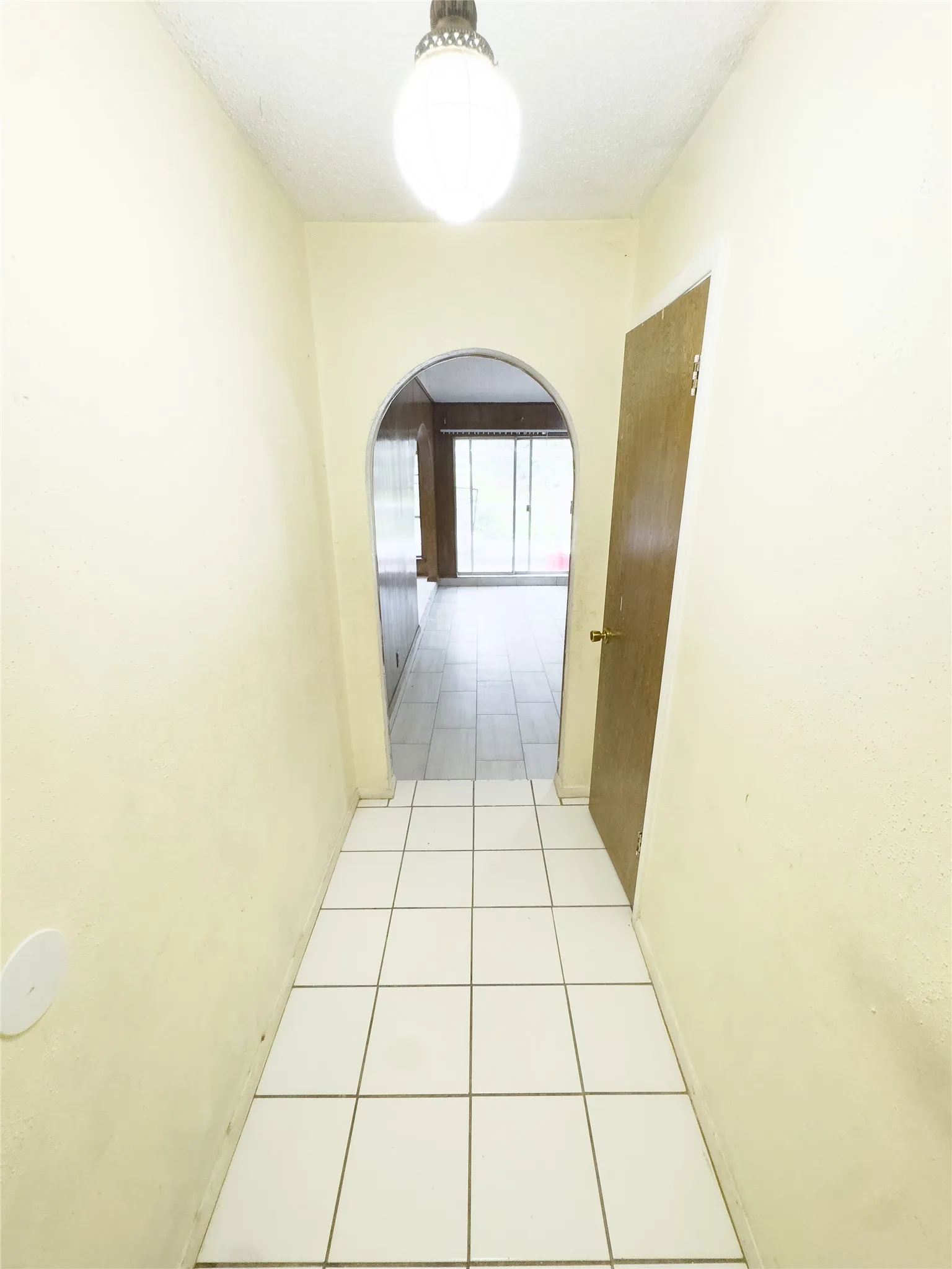 White square-tiled flooring leading to an arched doorway