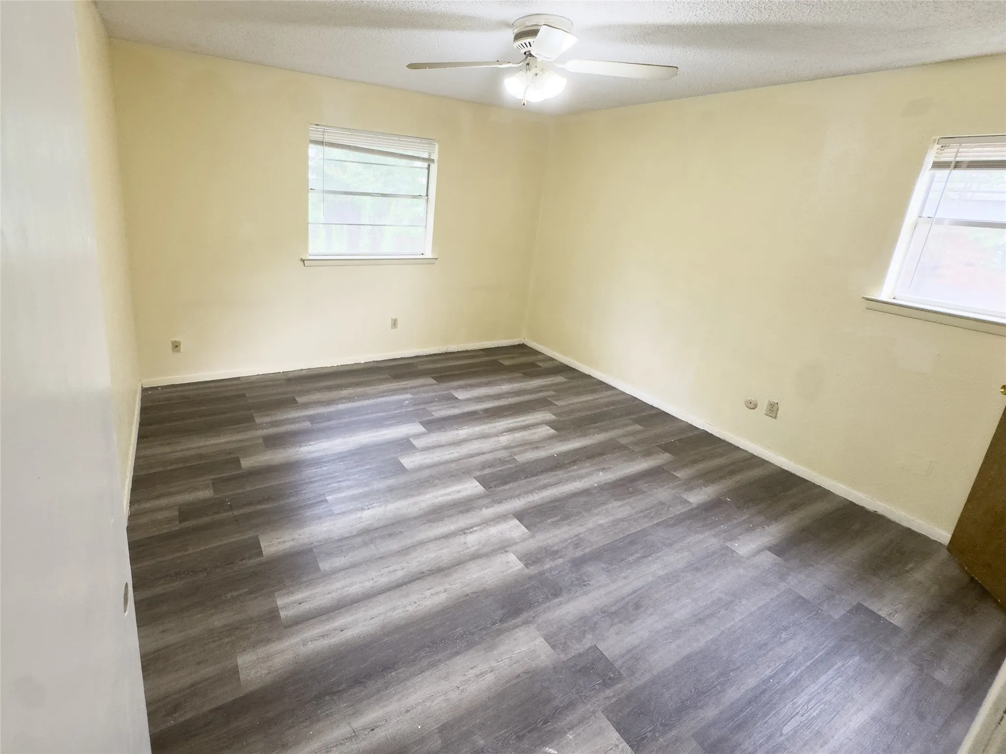 Wood-finish flooring throughout, bright walls, and a ceiling fan with integrated lighting