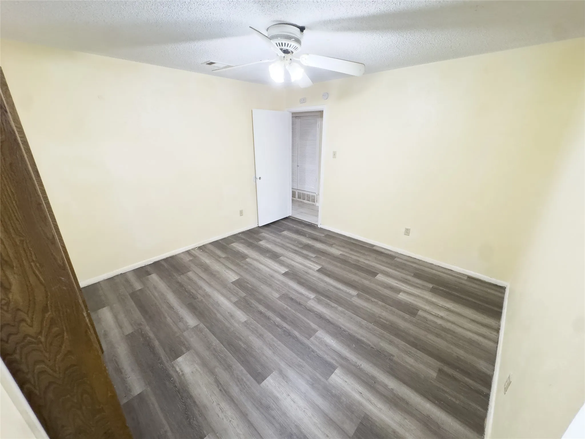 Wood-finish flooring with light-toned walls and a ceiling fan