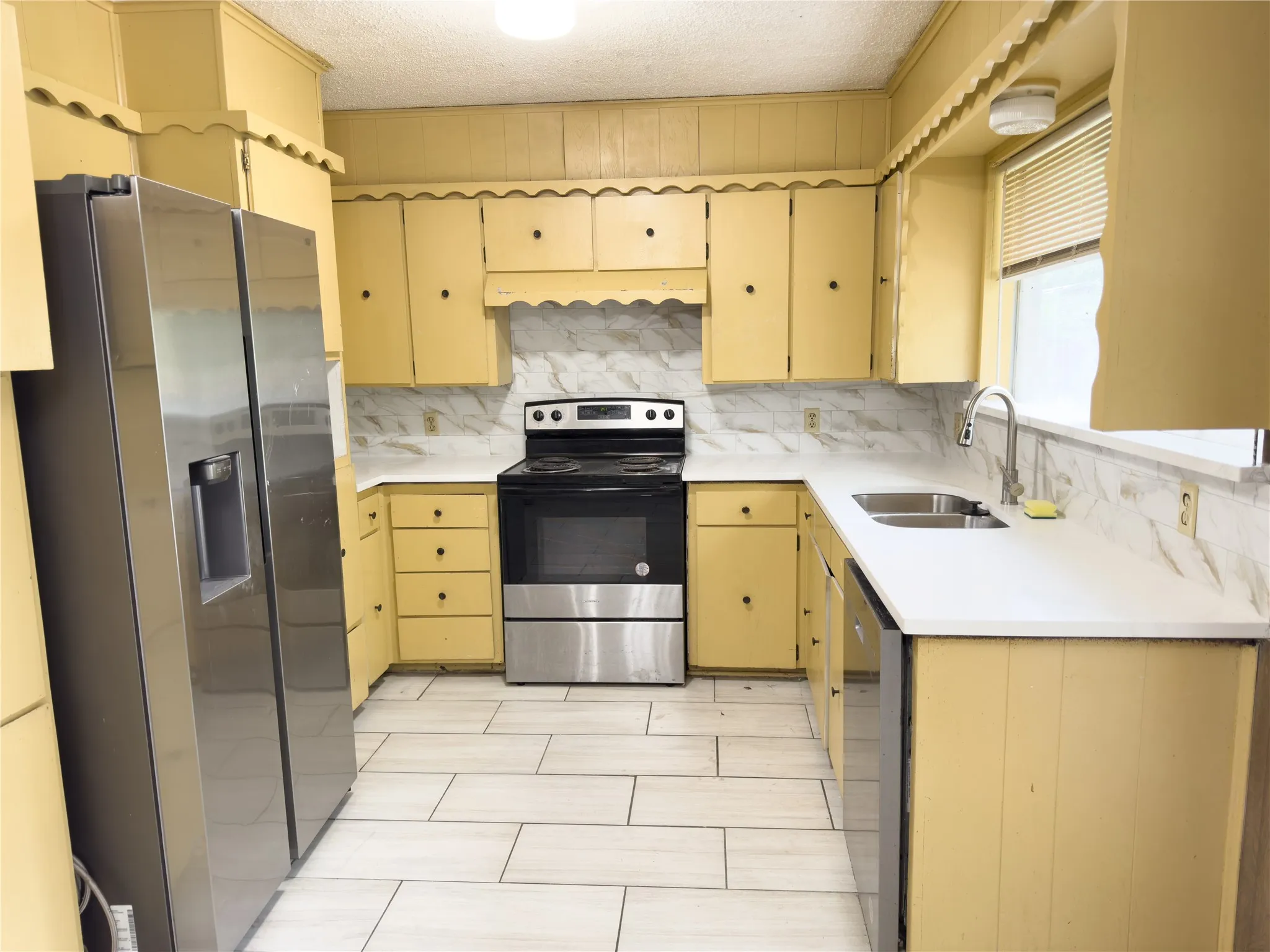 U-shaped kitchen featuring wood-finish cabinetry, a stainless steel refrigerator, a stainless steel range, and a dual basin sink