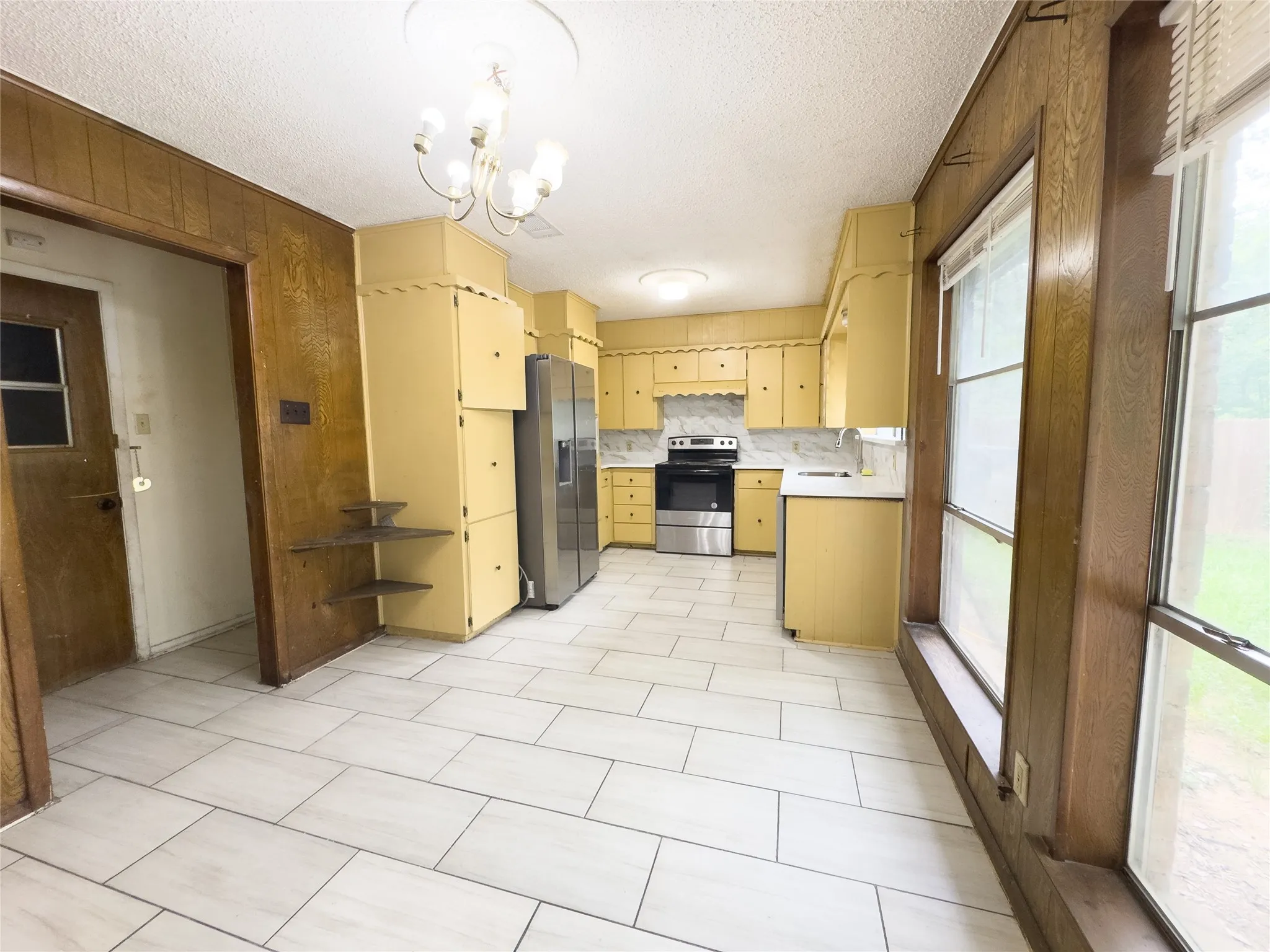 Kitchen featuring light-colored tile flooring, yellow cabinetry, and stainless steel appliances