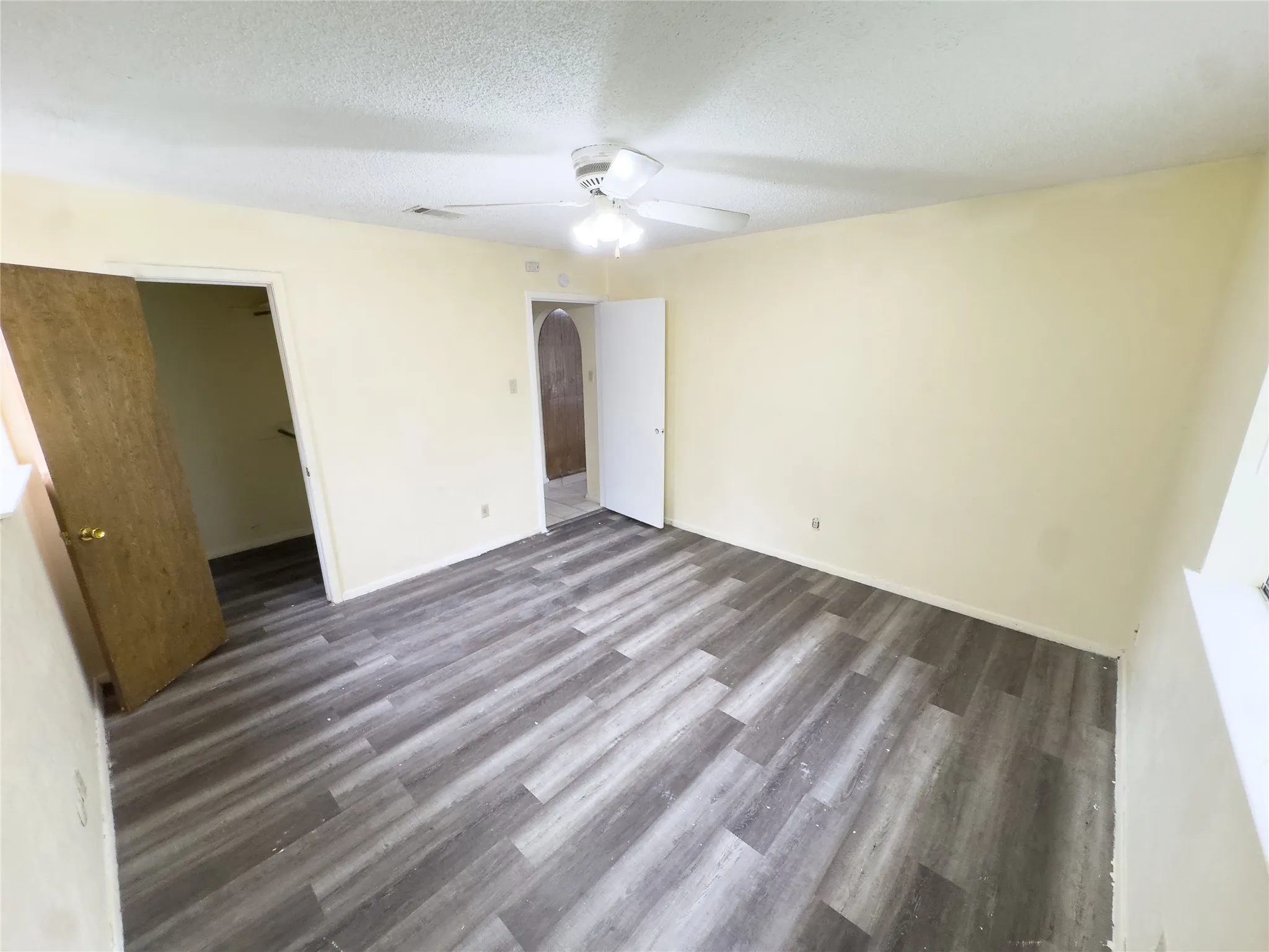 Wood-finish flooring with light-toned walls and a ceiling fan