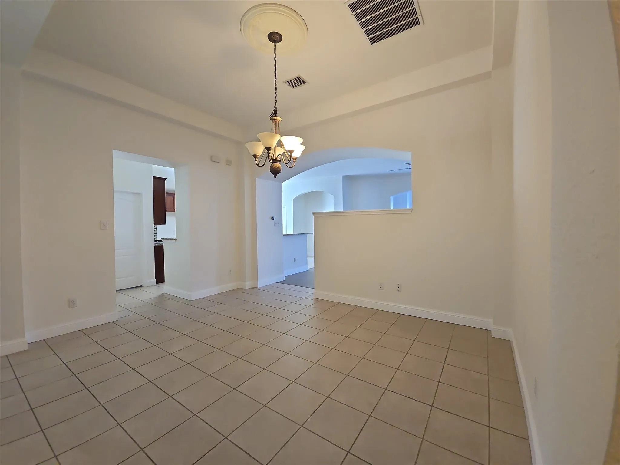 Recessed ceiling design, decorative ceiling medallion, multi-light chandelier, tile flooring, arched doorways
