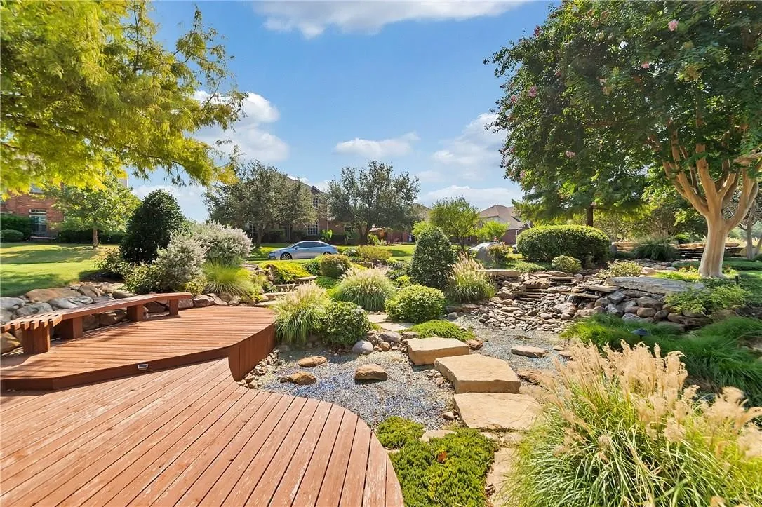 Curved wood deck with built-in bench, natural stone landscaping, and mature trees