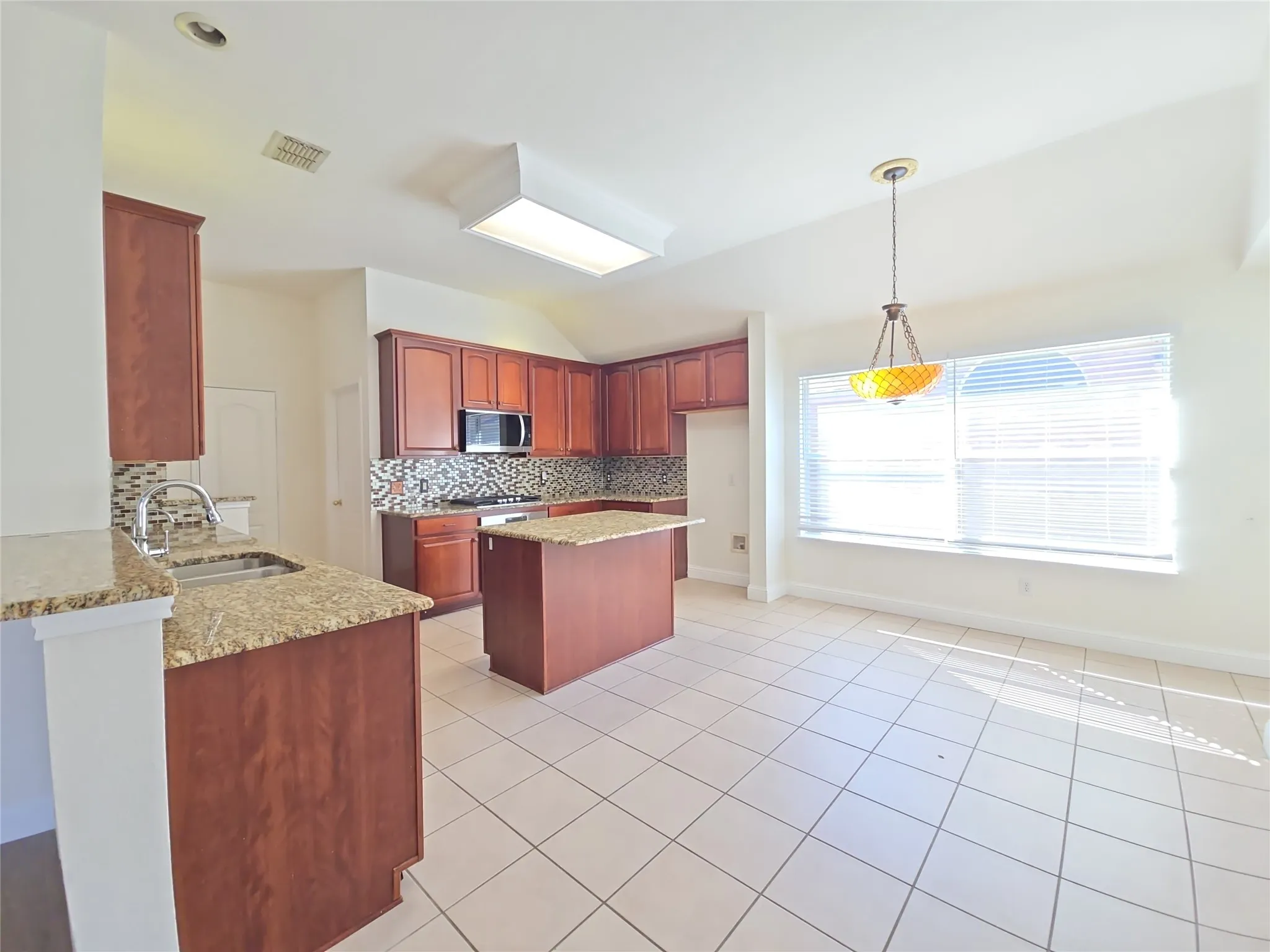 Kitchen featuring wood cabinetry, a center island, granite countertops, and a tile backsplash