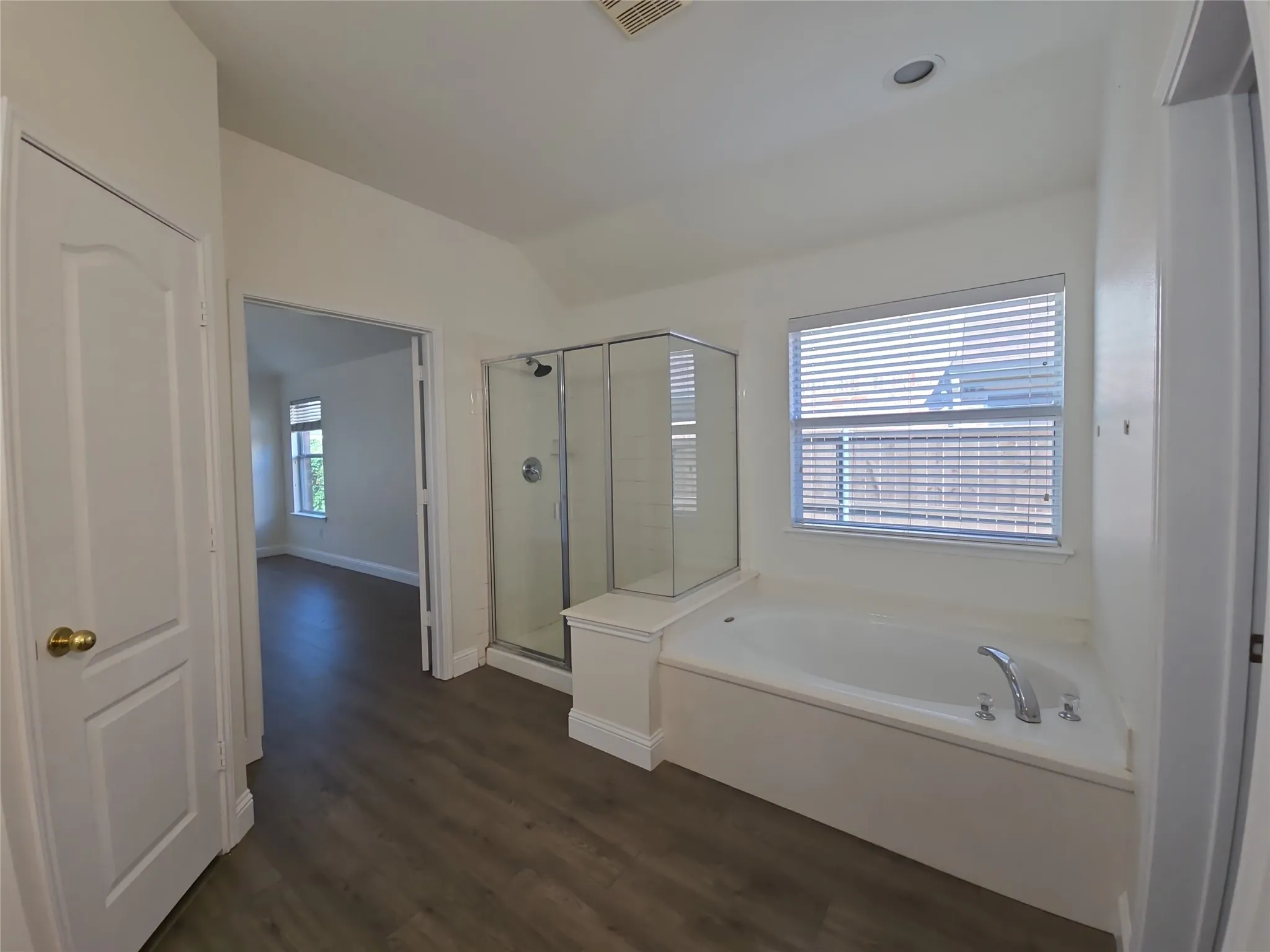 Enclosed glass shower, built-in soaking tub, wood-finish flooring, and recessed ceiling lighting