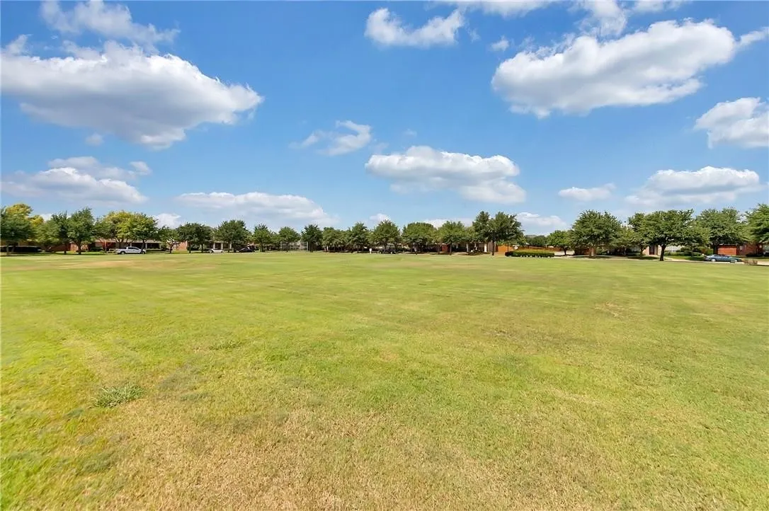Expansive green space featuring a large grassy area and mature trees