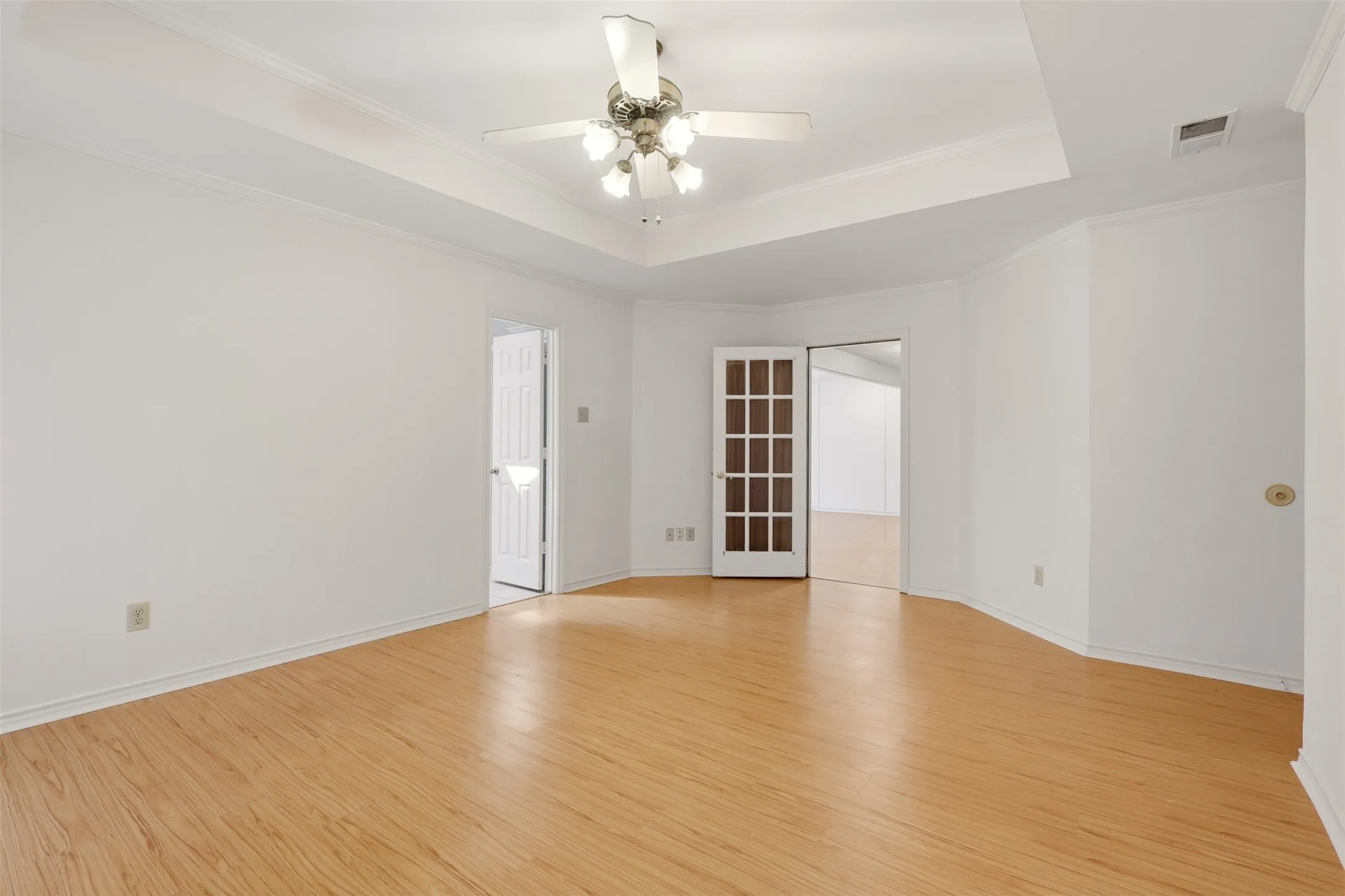 Wood-finish flooring, tray ceiling, and a ceiling fan with integrated lighting