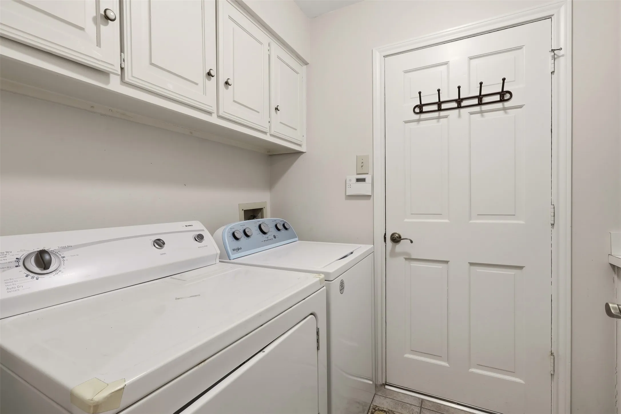 White cabinetry, paneled door, and tiled flooring