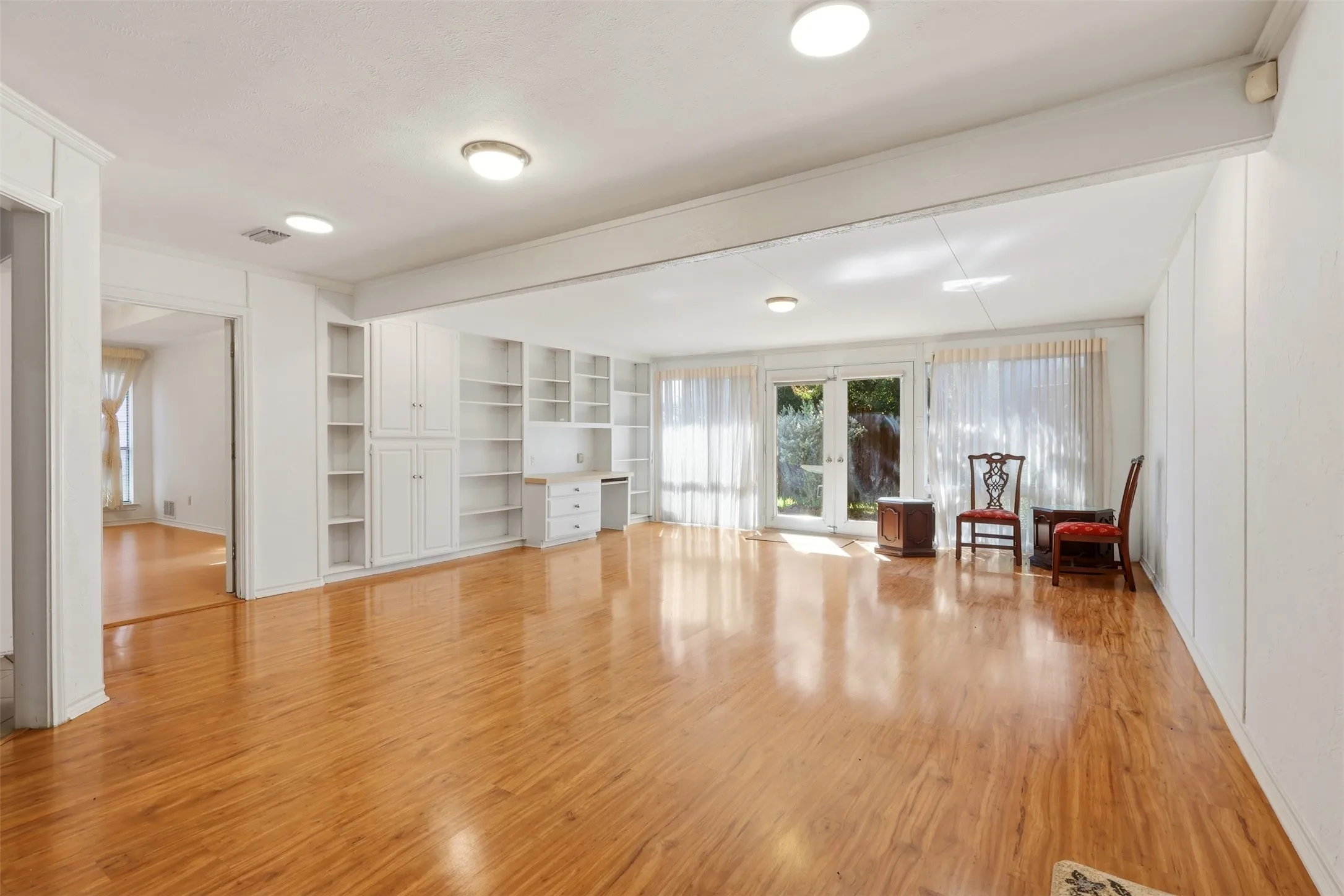 Hardwood-finish flooring throughout, featuring built-in white cabinetry, recessed lighting, and double-paned glass doors