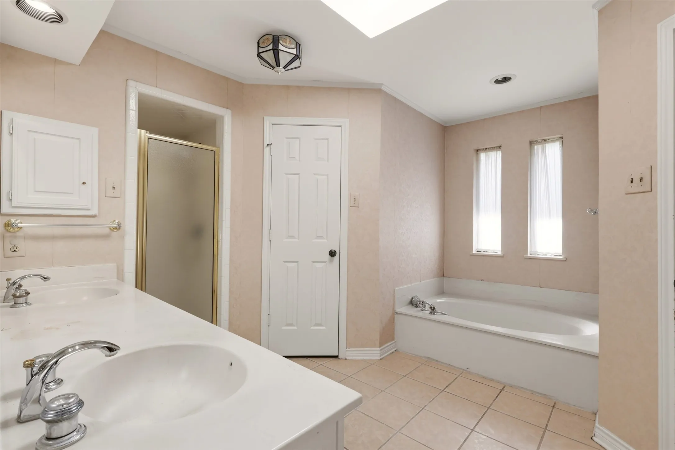 Dual vanity with integrated sinks, built-in soaking tub, and a separate glass-enclosed shower