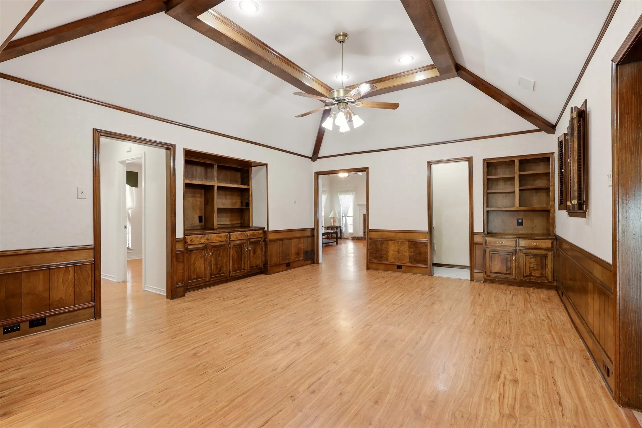 Vaulted ceiling with exposed wood beams, wood-finish flooring, built-in cabinetry, and wood paneling