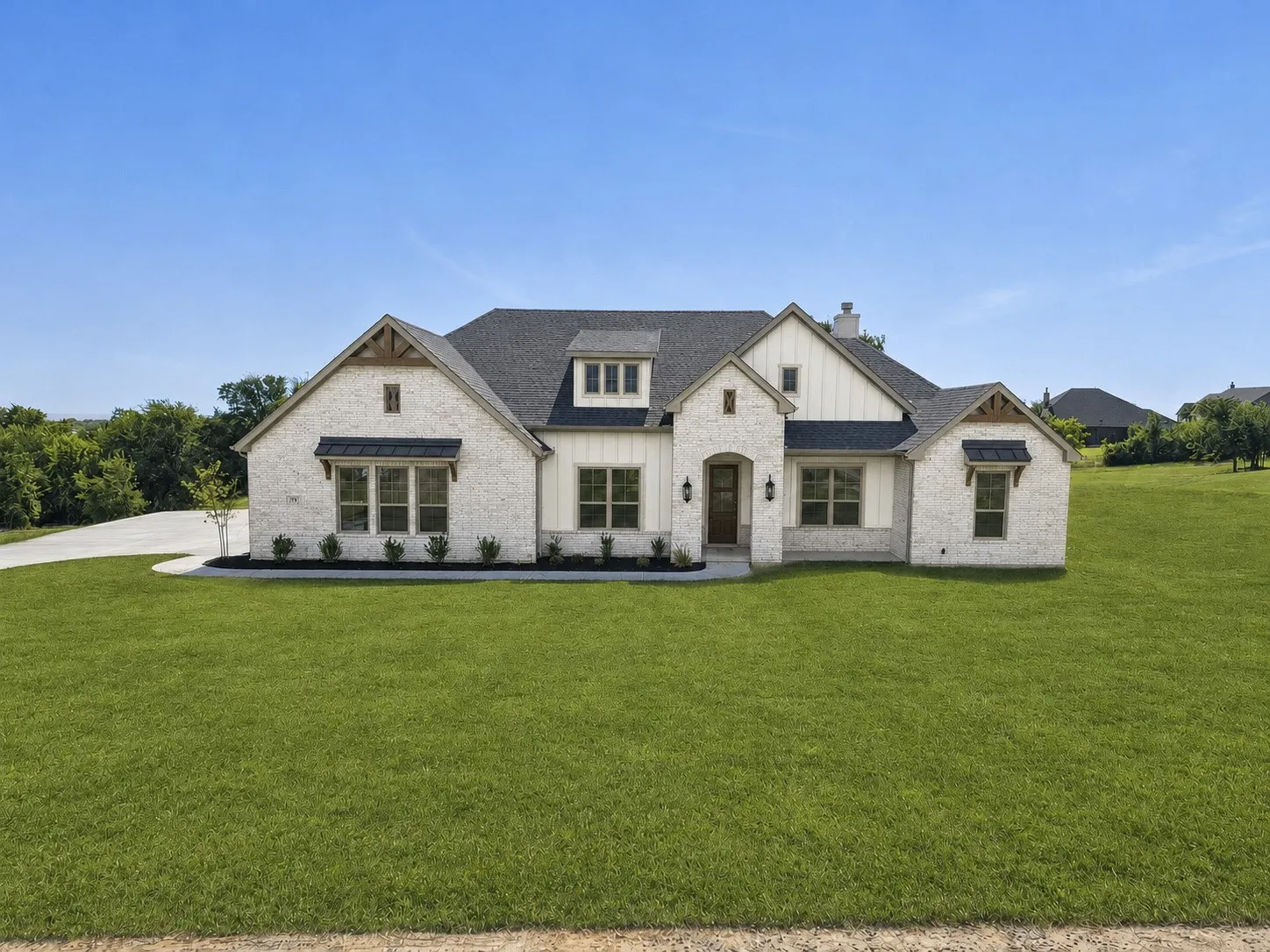White brick and board and batten exterior with a dark shingle roof, featuring multiple gables, and a concrete driveway